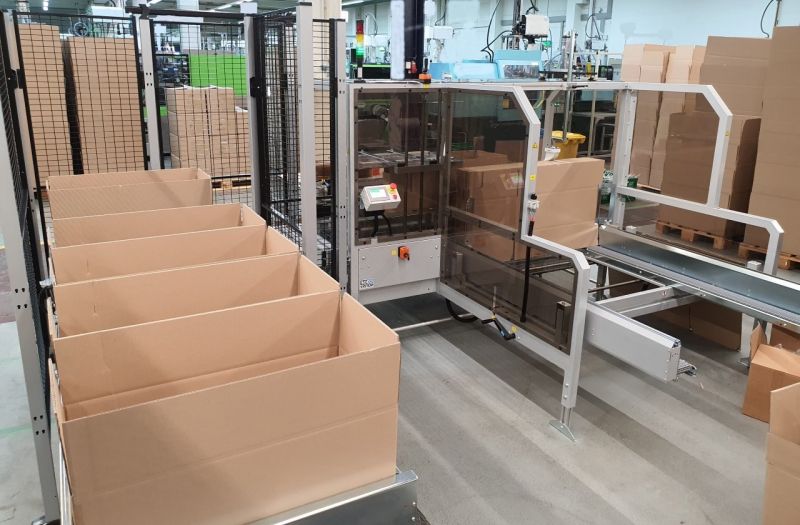 Kartonaufrichter faltet und verschließt Kartons in Serie Kartonaufrichter faltet und verschließt Kartons in Serie